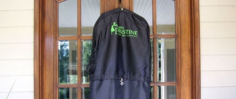 Garment bag from pristine dry cleaning hanging on a front door.