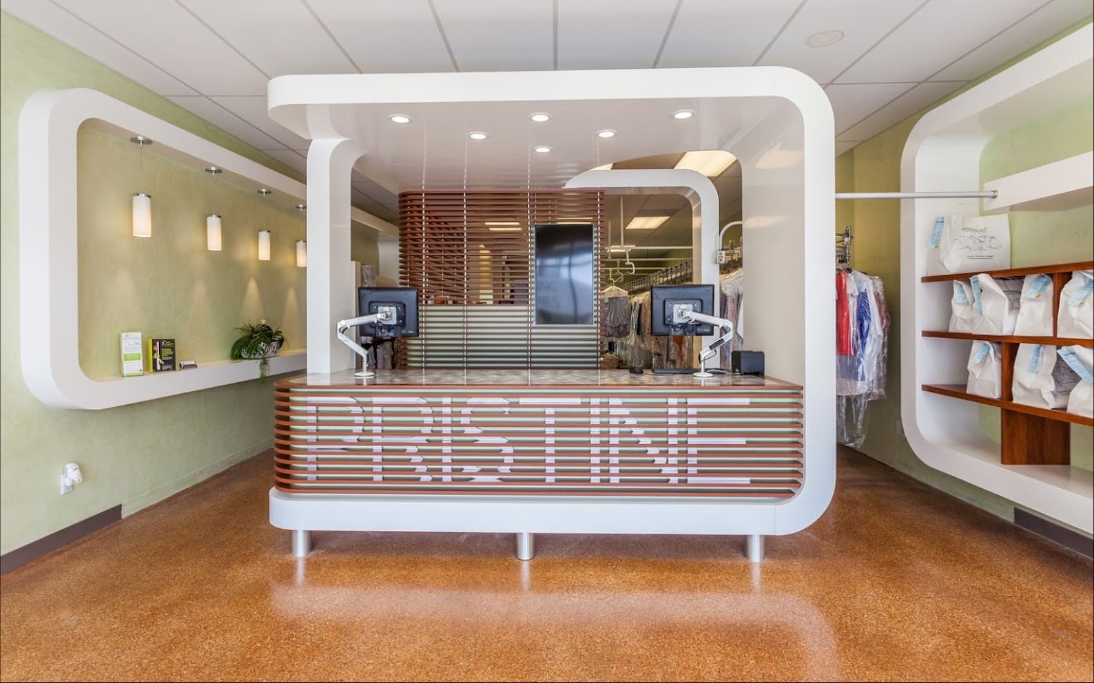 Modern hotel lobby with a curved reception desk, stylish lighting, and decorative shelving with folded towels.