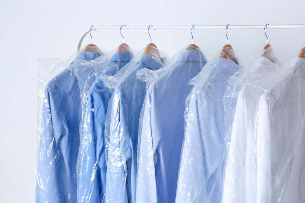 Person folding and stacking clothes on a table.