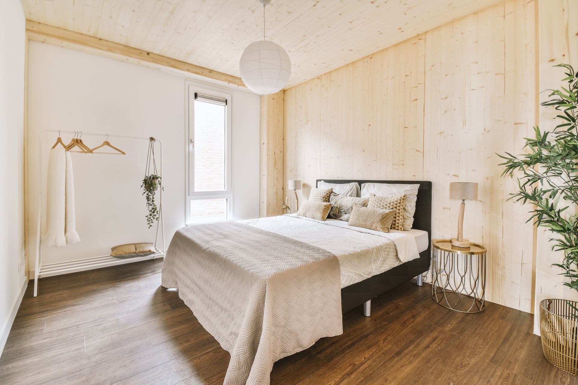 Two people are lying on massage tables, covered with dark towels. A person in a white robe stands nearby, holding a glass. The setting appears to be a spa or relaxation room.